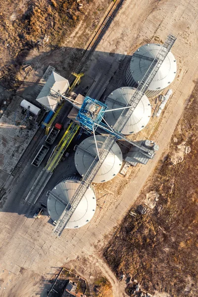 Visão de cima para baixo moderna aço agrícola grão celeiro silos armazém de armazenamento de cereais carregando transportador de grãos de carga ao pôr do sol. Atribuição de terras agrícolas paisagem da indústria rural. Instalação da loja de moinhos — Fotografia de Stock