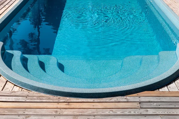 Új modern üvegszálas műanyag uszoda bejárat lépés tiszta friss, frissítő kék víz fényes forró nyári napon udvaron vagy üdülőszálloda spa területén. Tölgyfa vagy vörösfenyő padlóburkoló lap — Stock Fotó