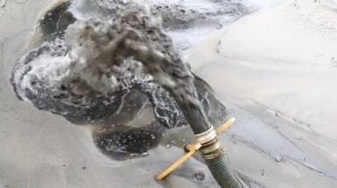 Güç pompası makinesinin yakın plan büyük borusu yere kum ve alüvyonlu çamur atığı suyu döküyor. Kum temizleme ve kıyı kesme. Septik kanalizasyon bakım servisi. İlkbahar sel felaketi