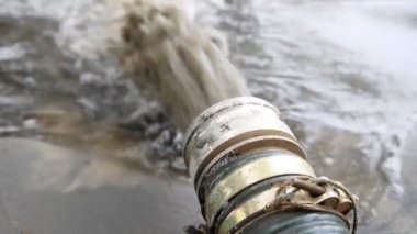 Güç pompası makinesinin yakın plan büyük borusu yere kum ve alüvyonlu çamur atığı suyu döküyor. Kum temizleme ve kıyı kesme. Septik kanalizasyon bakım servisi. İlkbahar sel felaketi
