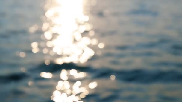 Desenfocado abstracto borroso hermoso dramático escénico brillante vibrante ola azul ondulaciones con luz solar cálida en la mañana del amanecer en la superficie del agua del lago o río. Línea de costa horizonte en el fondo — Vídeo de stock