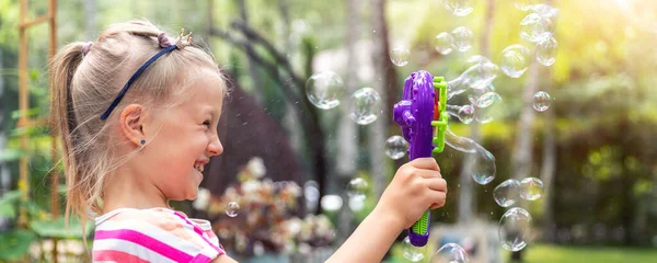 Portret van schattige kleine bond kid meisje genieten van plezier spelen blazen zeepbellen thuis tuin buiten op heldere warme zomerdag tegen gazon en bomen. Kind gezond buiten de natuur activiteiten — Stockfoto