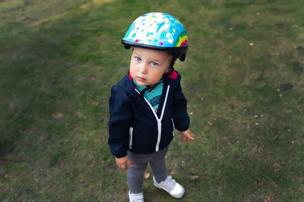 Carino piccolo adorabile caucasico felice bambino in casco di sicurezza chiedere cercando di divertirsi equitazione calcio scooter, gita in bicicletta seggiolino per bambini all'aperto. Concetto di attività sportiva di sicurezza per bambini attiva — Foto Stock