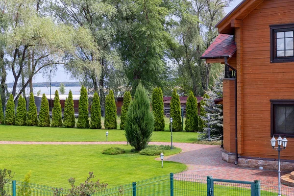 Righe appena falciate di prato verde alla villa di lusso cottage residenza di campagna. siepe recinzione di cedri thuja freschi. Progettazione del paesaggio e concetto di giardinaggio. Impianto e cantiere servizio di cura della flora — Foto Stock