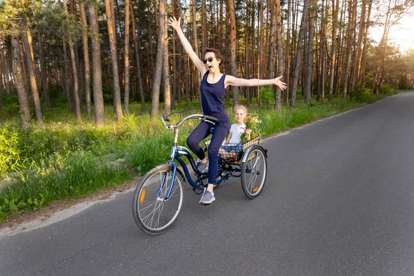 Fiatal felnőtt kaukázusi anya élvezi, hogy szabadidős szórakoztató lovaglás kerékpár aranyos imádnivaló szőke lánya gazdaság vad mező virág festői vidéki országút fényes napos napon. Vidéki vakáció — Stock Fotó