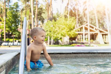 Küçük sevimli, sevimli, sarışın, oyuncu, beyaz tenli, aktif çocuk yaz mevsiminde açık deniz ormanı bölgesinde bilardo oynamaya bayılıyor. Mutlu çocuk arkadaş tatil gezisi konsepti