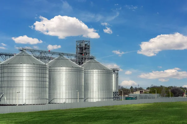 Scenic view of big modern steel agricultural grain granary cereal bin storage warehouse against blue sky. Агропромышленные сельскохозяйственные угодья сельских районов. Мельничный склад — стоковое фото