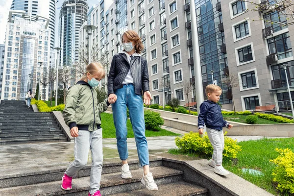 Giovane madre caucasica adulta che cammina al piano di sotto insieme a figlio e figlia bambini nel centro della città contro edificio. Nuovo stile di vita normale persone urbane post coronavirus vita — Foto Stock