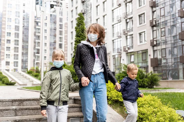 Joven madre caucásica adulta caminando abajo junto con hijos e hijas en el centro de la ciudad contra la construcción. Nueva vida normal urbana estilo de vida post coronavirus — Foto de Stock