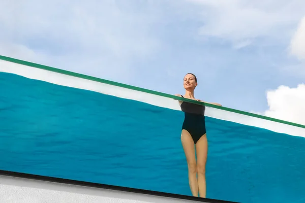 Молоді дорослі кавказькі спортивні стрункі усміхнені розслабляючі жінки насолоджуються стояти в басейні з чистою блакитною водою і відчайдушною стіною на небі на розкішному курорті. Здоровий спосіб життя та концепція здоров'я — стокове фото