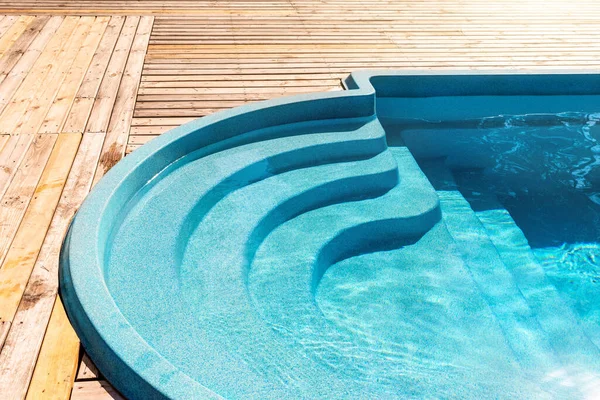 Nuevo paso moderno de la entrada de la piscina de plástico de fibra de vidrio con agua azul fresca fresca y refrescante en el día de verano caliente brillante en el patio o en la zona de spa del hotel del complejo. Piso de madera cubierta de teca o tabla de alerce — Foto de Stock