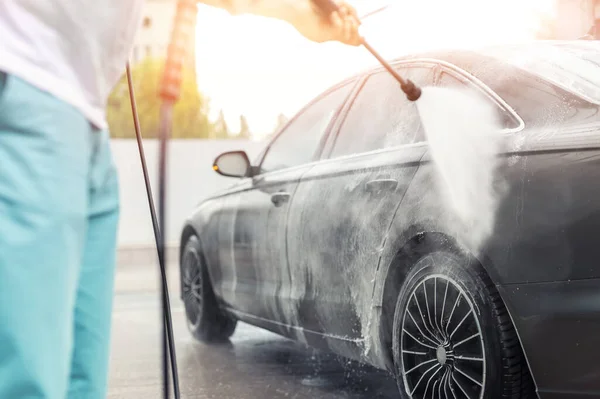 Detailaufnahme Autowäsche mit Hochdruck-Wasserpumpe am Selbstbedienungsautomaten im Freien an einem strahlend schönen Sommertag. Fahrzeug mit Schaumstoff-Shampoo chemische Reinigungsmittel während der Autowäsche Selbstbedienung abgedeckt — Stockfoto