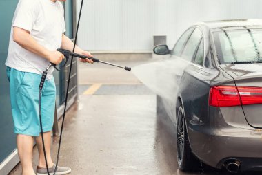 Aydınlık bir yaz gününde self-servis açık havada yüksek basınçlı su teçhizatı pompasıyla yakın plan araba yıkama. Araba oto yıkama servisi sırasında köpük şampuanla kaplı kimyasal deterjanlar.