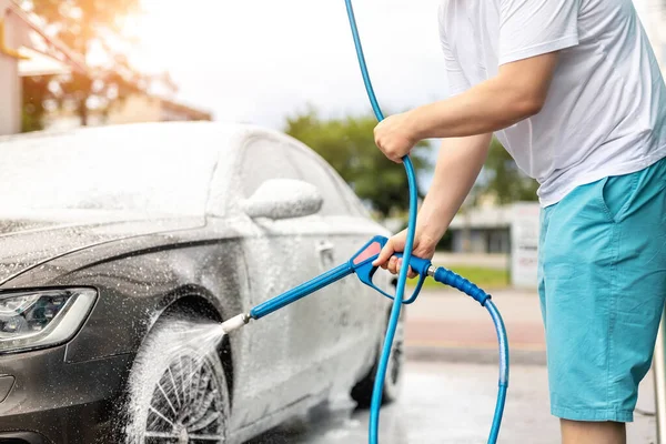 Detailaufnahme Autowäsche mit Hochdruck-Wasserpumpe am Selbstbedienungsautomaten im Freien an einem strahlend schönen Sommertag. Fahrzeug mit Schaumstoff-Shampoo chemische Reinigungsmittel während der Autowäsche Selbstbedienung abgedeckt — Stockfoto