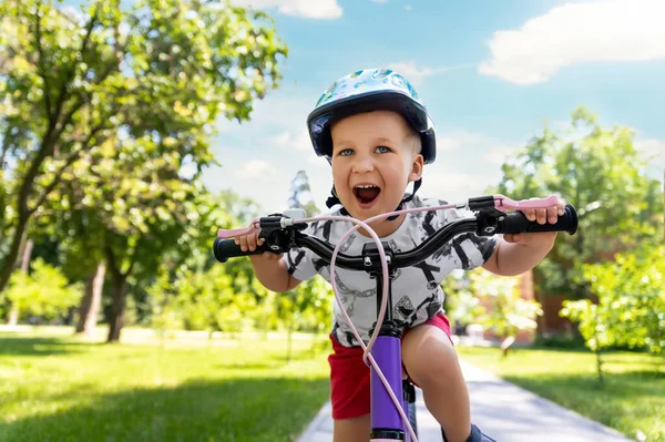 Retrato pouco bonito adorável caucasiano criança menino em capacete de segurança desfrutar de ter divertido andar de bicicleta exercício no parque da cidade estrada jardim floresta. Primeira bicicleta infantil. Crianças ao ar livre esporte atividades de verão — Fotografia de Stock