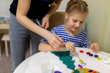 Anne ve çocuk birlikte yeni yılı tahta, doğal köknar ağacı oyuncağını yeşil renge boyuyorlar. Mutlu çocuk el yapımı Xmas sanat dekorasyonu konsepti yapıyor. Çocuklar evde hobi olarak ölüyorlar.