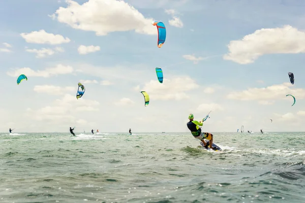 Panoramic view of many people enjoy riding kite surf board in sun uv protection suit on bright sunny day at sea or ocean shore kitesurfing camp spot. Watersport adrenaline fun adventure acitivity — Stock Photo, Image