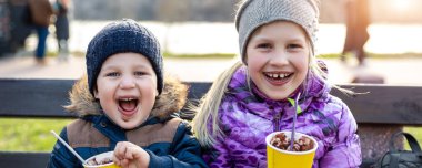 İki sevimli kardeş bankta oturur lezzetli sıcak çikolata içerler şehir parkında ya da arka bahçede yürürken kağıt bardaklardan çay kakaosu içerler. Erkek ve kız kardeş eğlenin.