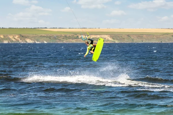 Young adult caucasian fit male person enjoy riding kite surf board making extreme trick stunt bright sunny day against blue sky at sea or ocean shore. Watersport adrenaline fun adventure acitivity — Stock Photo, Image