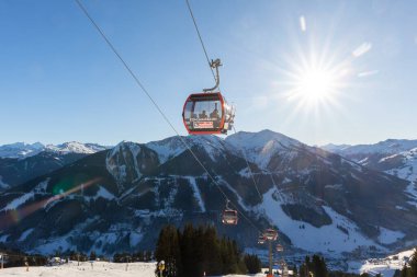 Saalbach-Hinterglemm, Avusturya - 30 Aralık 2024. Güneşli kış günü Alp yamacında kar kayakları Kohlmaisbahn gondol istasyonu. Parlak mavi gökyüzü dağı Saalbach-Hinterglemm kayak sirki panoraması