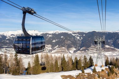 Yeni modern geniş kabin kayak teleferiği kar kaplı orman ağacı ve dağ zirvelerine karşı lüks kış dağları tatil beldesinde kar manzarasıyla kaplı. Kış sporları, eğlence ve seyahat.
