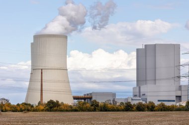 Muazzam soğutma kulesi enerji santrali Saksonya Almanya buharlı bulutlu gökyüzünü serbest bırakıyor. Alanlarla çevrili sanayi kompleksi modern enerji üretimini, altyapı çevre teknolojisini gösteriyor.