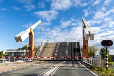 Modern asma köprü açık mavi gökyüzü ve Hollanda 'da kırmızı trafik ışıkları güvenlik bariyerleri var. Hollanda mühendislik yapısı, hareket halindeki kentsel altyapıyı gösteren kanalları birbirine bağlıyor.