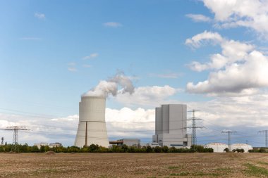 Muazzam soğutma kulesi enerji santrali Saksonya Almanya buharlı bulutlu gökyüzünü serbest bırakıyor. Alanlarla çevrili sanayi kompleksi modern enerji üretimini, altyapı çevre teknolojisini gösteriyor.
