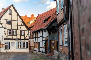 Kereste çerçeveli evleri olan dar kaldırım taşı caddeleri sıcak gün ışığında parlıyor. Quedlinburg manzarası ortaçağ cazibesini, renkli çatıları ve tarihi Alman kasabasının barışçıl atmosferini yakalıyor..