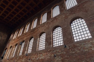 Uzun kemerli camları, tuğla duvarları ve ritmik şablonları olan tarihi bazilika iç mimarisi. Yumuşak gün ışığı kutsal atmosferi şekillendirir, geometri, ölçek ve sakin mimari mirası ortaya çıkarır..