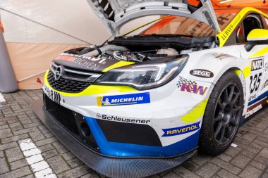 Oschersleben, Almanya - 21 Eylül 2025: Motor spor etkinliği sırasında açık kaputlu yarış arabası, motor bölmesi, aerodinamik kaporta, sponsor çıkartmaları ve pit alanının içindeki yarış lastiklerini gösteriyor.