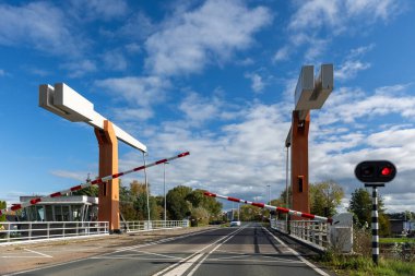 Modern asma köprü açık mavi gökyüzü ve Hollanda 'da kırmızı trafik ışıkları güvenlik bariyerleri var. Hollanda mühendislik yapısı, hareket halindeki kentsel altyapıyı gösteren kanalları birbirine bağlıyor.