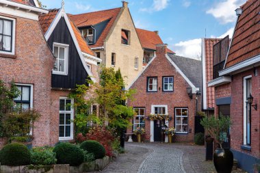 Ootmarsum 'da hoş bir cadde. Tuğladan evler ve kaldırımlar boyunca kaldırımlar, yeşilliklerle çerçevelenmiş. Resimli Hollanda şehir manzarası rahat mimari ve sakin köy havasını gösteriyor.