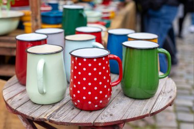 Renkli diş minesi kupaları kırsal ahşap masa tezgahı düzenledi. Klasik metal bardaklar parlak renkler polka desenli neşeli klasik kamp stili mutfak eşyaları popüler kahve çay pikniği kullanımı.