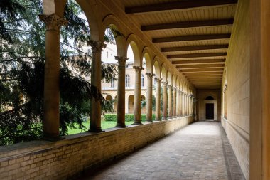 Uzun sütunlu koridor, tarihi Potsdam avlusunda taş kemerler, güçlü perspektif, sıcak ışık gölgesi. Neoklasik mimari, kumtaşı atari salonu, yeşil bahçenin yanındaki sessiz geçit..