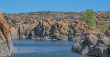 Watson Gölü 'nde parlak mavi suyla korunmasız granit kaya yatağı var. Prescott, Yavapai County, Arizona 'da. 