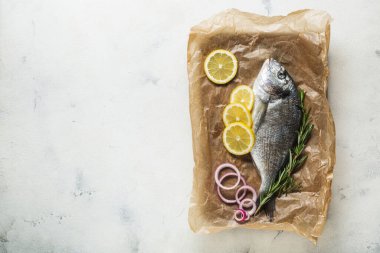 Çiğ Dorado balığı pişirmek için hazırlanmış eski bir tahta kesme tahtasının üzerinde..