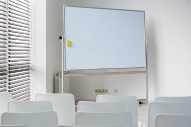 Modern ofiste büyük beyaz okul yönetim kurulu ve beyaz sandalyeli toplantı odası..