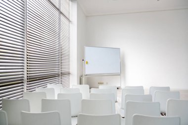 Modern ofiste büyük beyaz okul yönetim kurulu ve beyaz sandalyeli toplantı odası..
