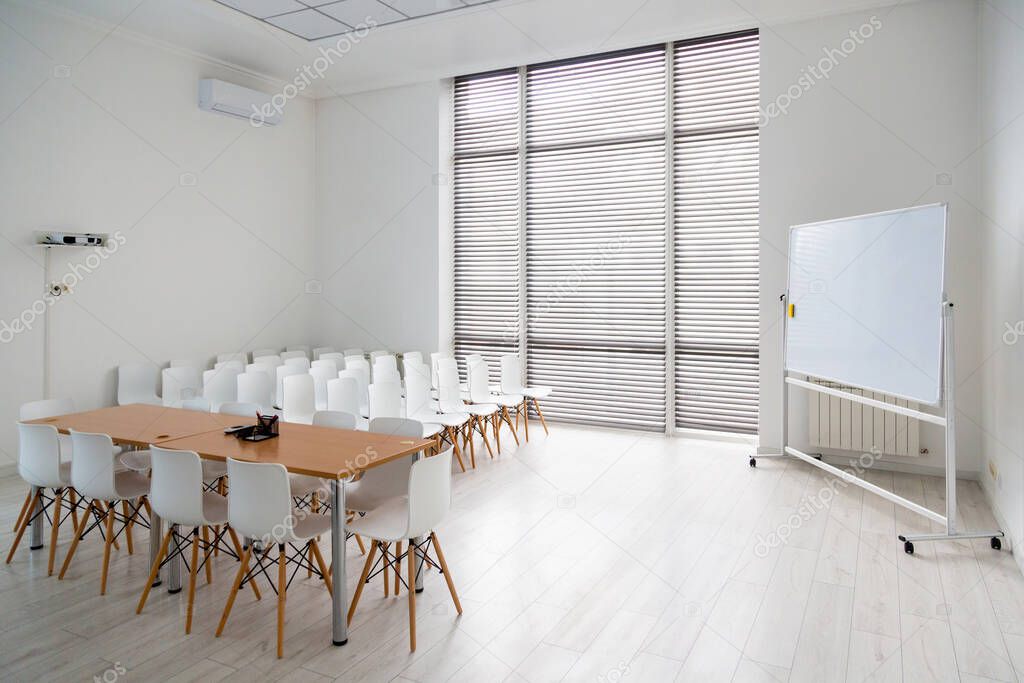 Meeting room with a large white school board and white chairs in modern office.