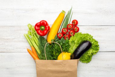 Beyaz ahşap bir arka planda kağıt bir torba içindeki ürünler. Süpermarketten ya da marketten alışveriş yapmak