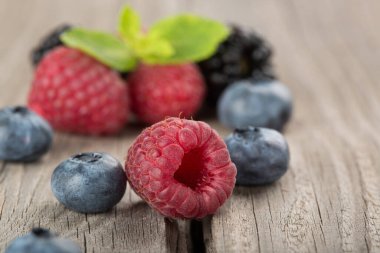 Çilek karışımı. Ahududu, yaban mersini ve böğürtlen eski ahşap bir yakın çekim masa