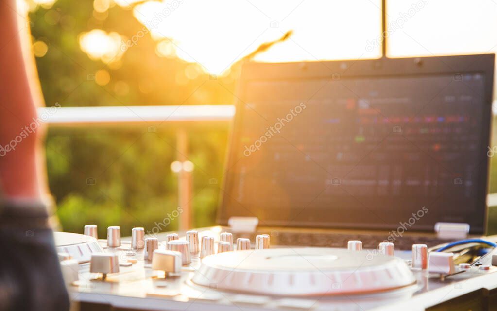 Dj mixing music outdoor. DJ stands near the control panel.