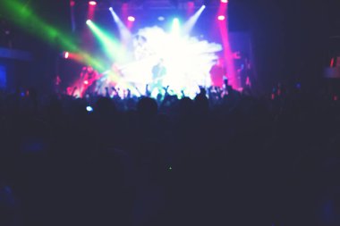 Büyük bir konser kulübünde konserin izleyicileri..