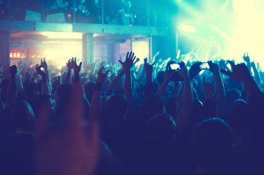 Büyük bir konser kulübünde konserin izleyicileri..