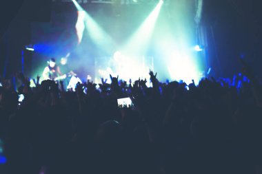 Büyük bir konser kulübünde konserin izleyicileri..