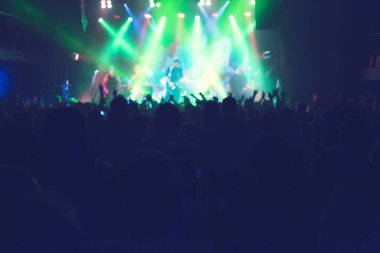 Büyük bir konser kulübünde konserin izleyicileri..