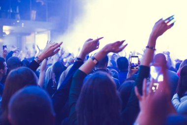 The audience watching the concert on stage in night concert club.
