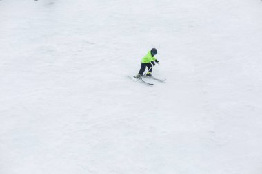 A child skiing alone down the hill at high speed.