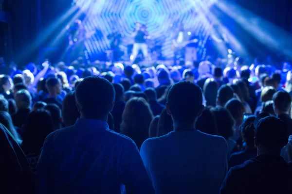 Büyük bir konser kulübünde konserin izleyicileri..